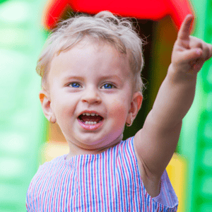 A smiling toddler pointing upward, reflecting how many words should an 18 month old say