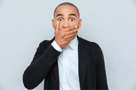 Man covering mouth in shock, possibly experiencing sudden speech problems in adults during conversation