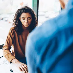 Woman appearing frustrated while speaking, possibly facing sudden speech problems in adults in public