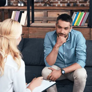 Man discussing communication difficulties, possibly seeking help for sudden speech problems in adults with therapist