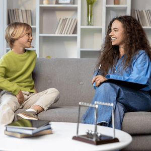 A young child smiles during puberphonia treatment with a speech therapist in a cozy office