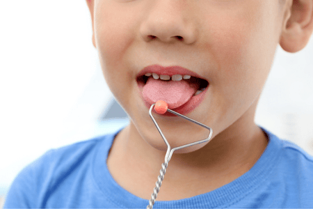 Child performs targeted tongue exercise to improve speech clarity affected by childhood dysarthria condition