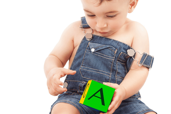 Baby holding a bright block while exploring letters and shapes during early learning activity