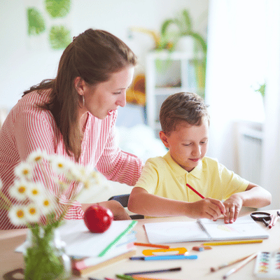 Mother helps child with writing activity to encourage language development and early literacy skills