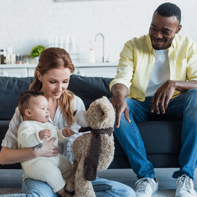 Parents engage baby with plush toy during playtime to foster emotional bonding and early communication