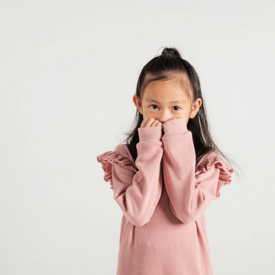 Little girl in pink sweater looking shy, possibly experiencing social anxiety or communication challenges
