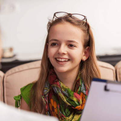 Smiling girl responds confidently during speech-language session, demonstrating improved articulation skills and growing self-esteem today