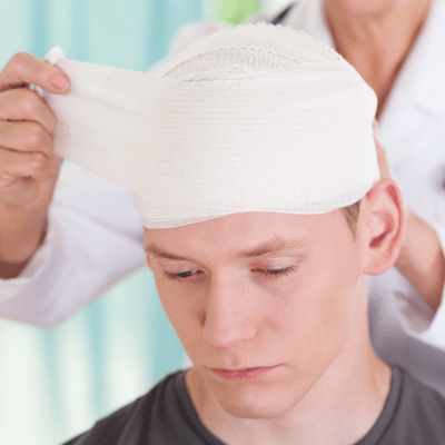 Medical professional wraps a bandage around a young man's head after an injury