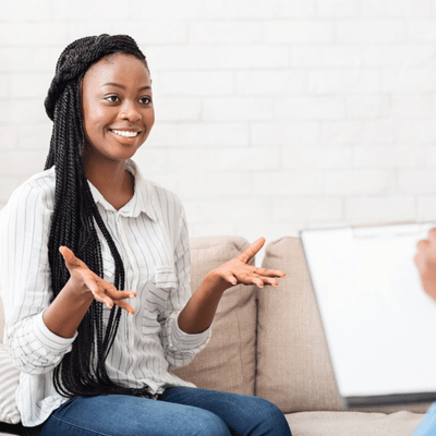Smiling woman engages in a counselling session, using open gestures while speaking to therapist