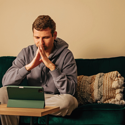 Stressed man leans toward tablet during home session of online speech therapy for adults today