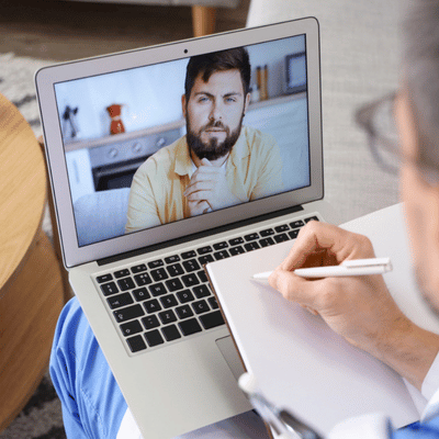 Therapist takes notes while video chatting with patient, providing online speech therapy for adults remotely